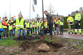 Wethouder Frank Groen (Tiel) helpt een handje bij het planten van de eerste boom.
