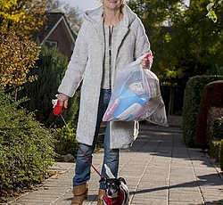 Vrouw brengt restafval weg met hondje